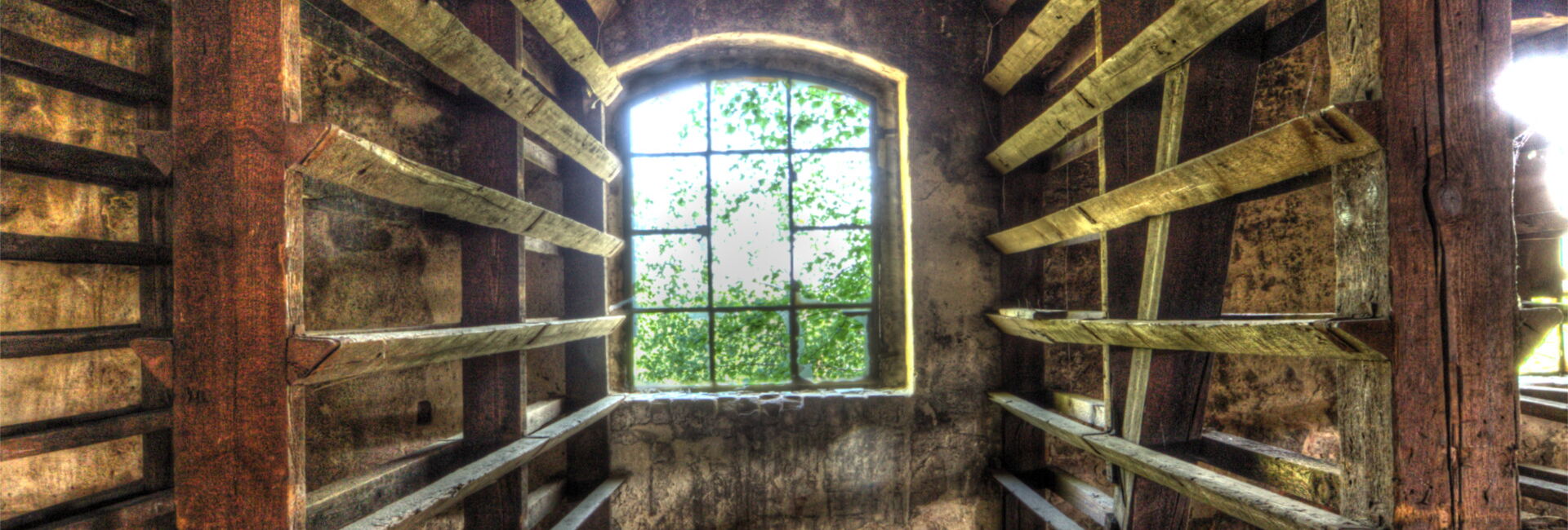 Verfallene Holzhalle mit Fenster und Regalen.